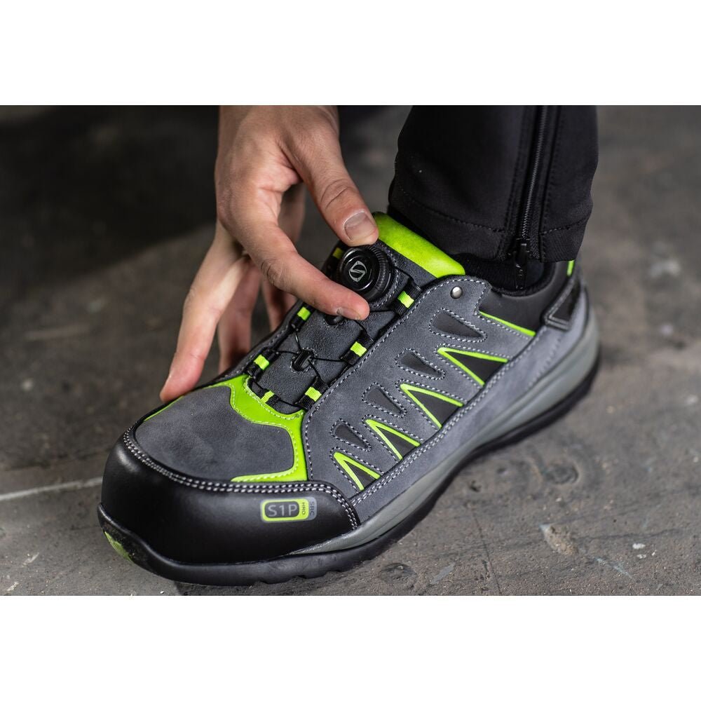 Gray and lemon athletic-style steel-toe shoes with padded collars, lace-up fronts, worn on concrete floor.